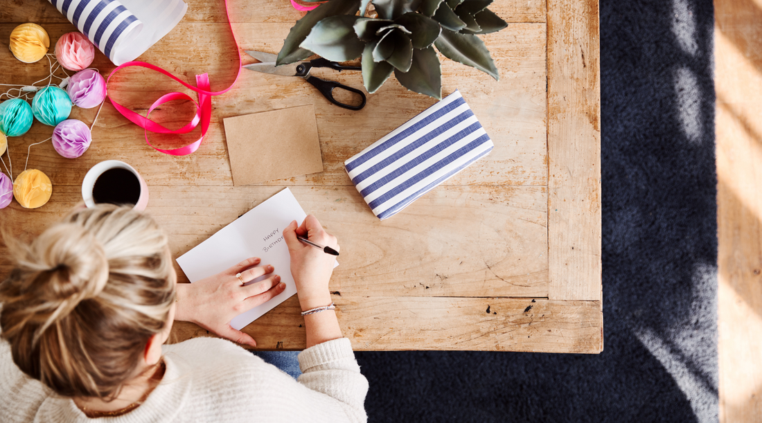 Woman writing Happy Birthday on a greeting card